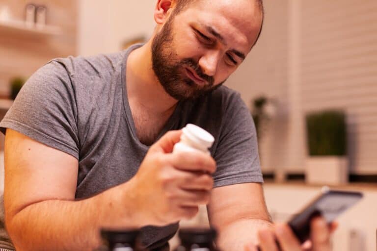 balding man holding bottle of pills